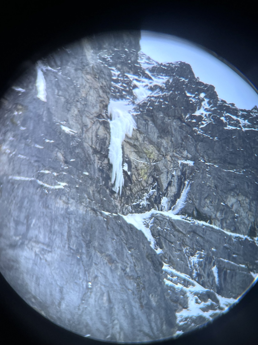 View through binoculars of the hanging dagger of Borrowed Time on the west face of Sloan Peak.