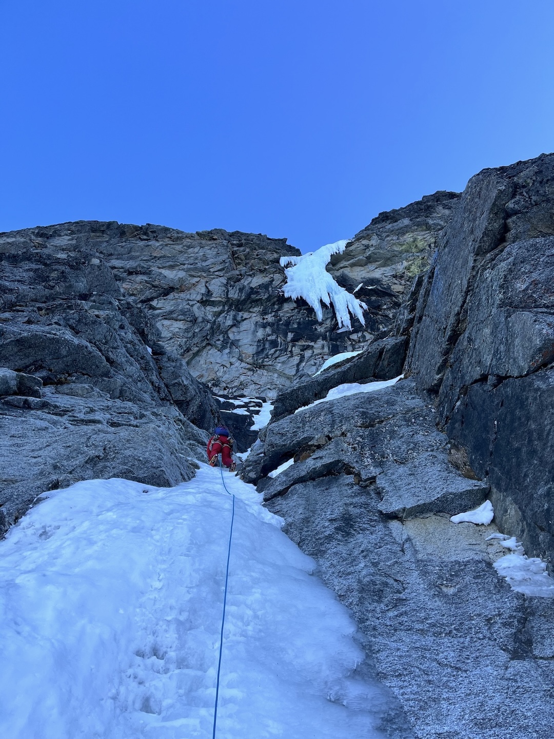  Justin Sackett leads through a narrow slot on pitch three of Borrowed Time (1,900’, IV WI5 M7) on Sloan Peak. The dagger of ice on the crux pitch looms above. 