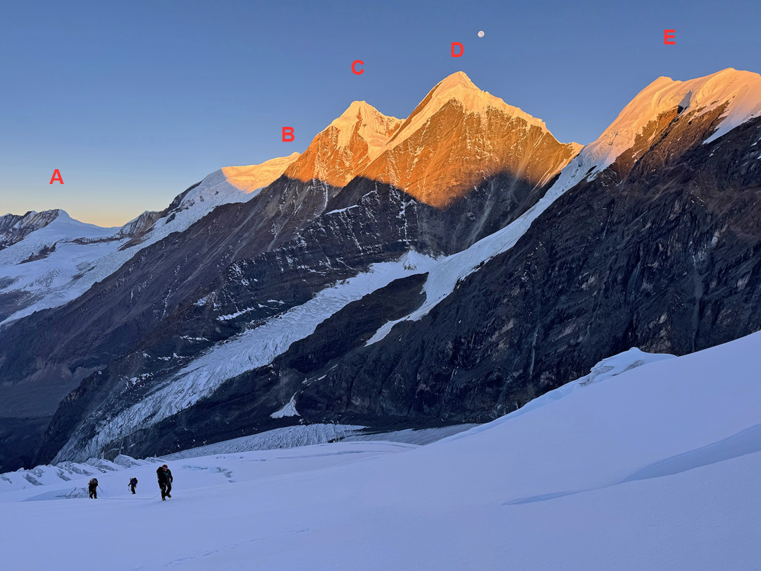 Ascending the southwest glacier of Sanctuary Peak with (in center) the Patrasi peaks catching the morning sun. (A) Peak 6,036m (climbed and named Hopeless Peak by Paulo Grobel, but not a defined summit on HMG-Finn map). (B) Kande Hiunchuli (6,627m). (C) Patrasi Main or West (6,521m). (D) Patrasi Northeast (6,450m). (E) Part of Peak 6,117m. 
