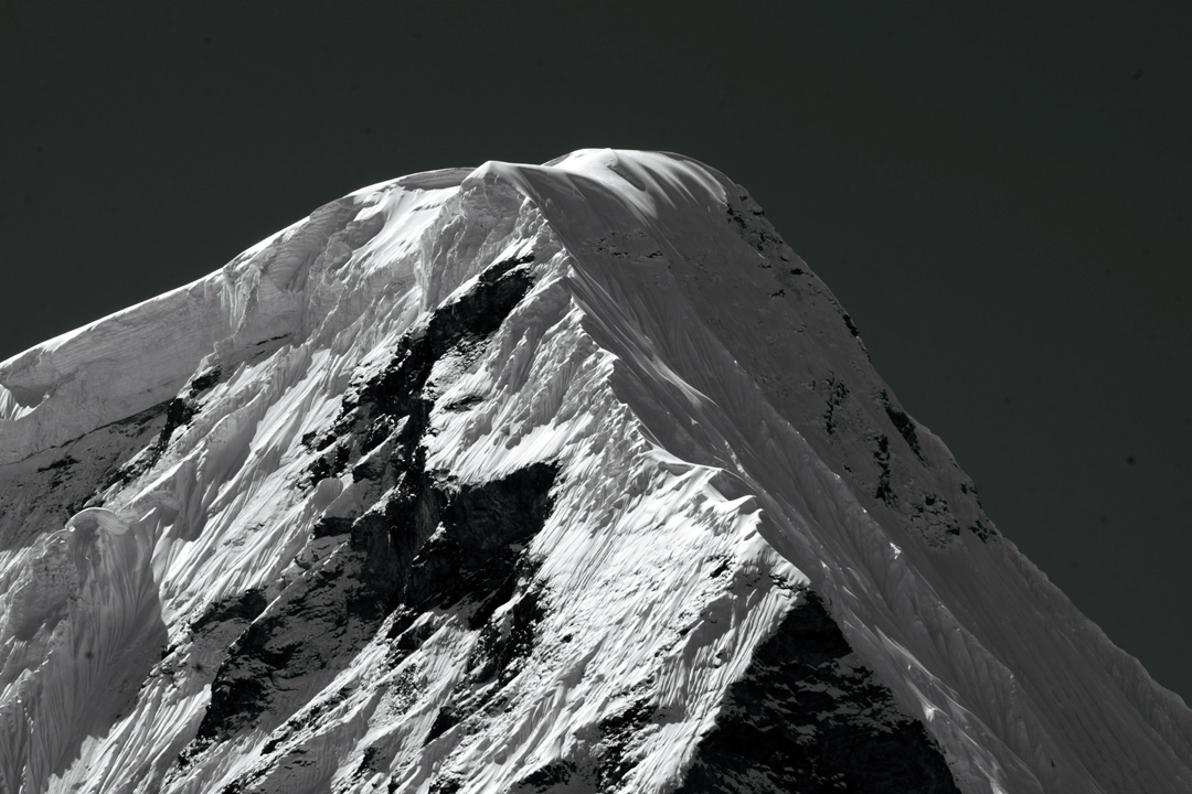 The upper section of the northeast pillar of Chobutse. The climbers gained the final ridge, facing the camera, by the snow and ice slope left of the rocky triangle in lower right.