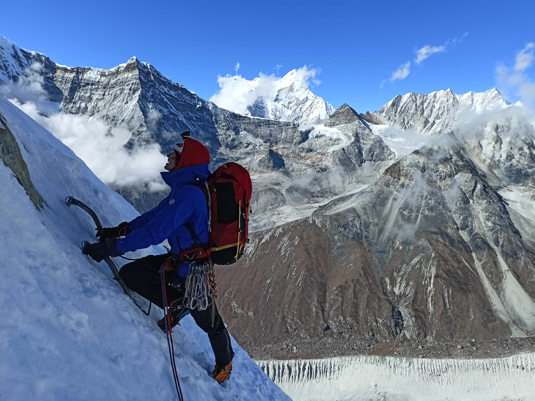 Maciej Kimel on the northeast pillar of Chobutse. Above the climber and across the lower Rolwaling Glacier is the pointed rocky summit of Omi Tso Go (6,322m) on the northeast ridge of Kang Nachugo. Behind, and much higher, is Menlungtse, while on the far right is the horizontally topped Langdung (6,357m).