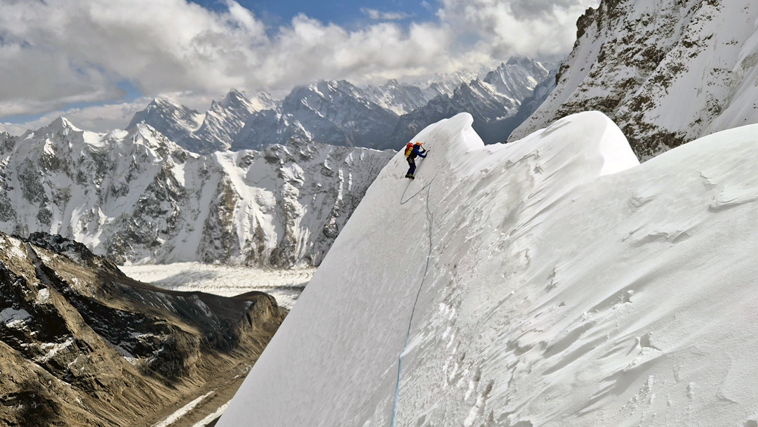 Louis Rousseau on the summit (south) ridge of Naseer Baig II. In the distance are high peaks of the Spantik-Sosbun Mountains. 