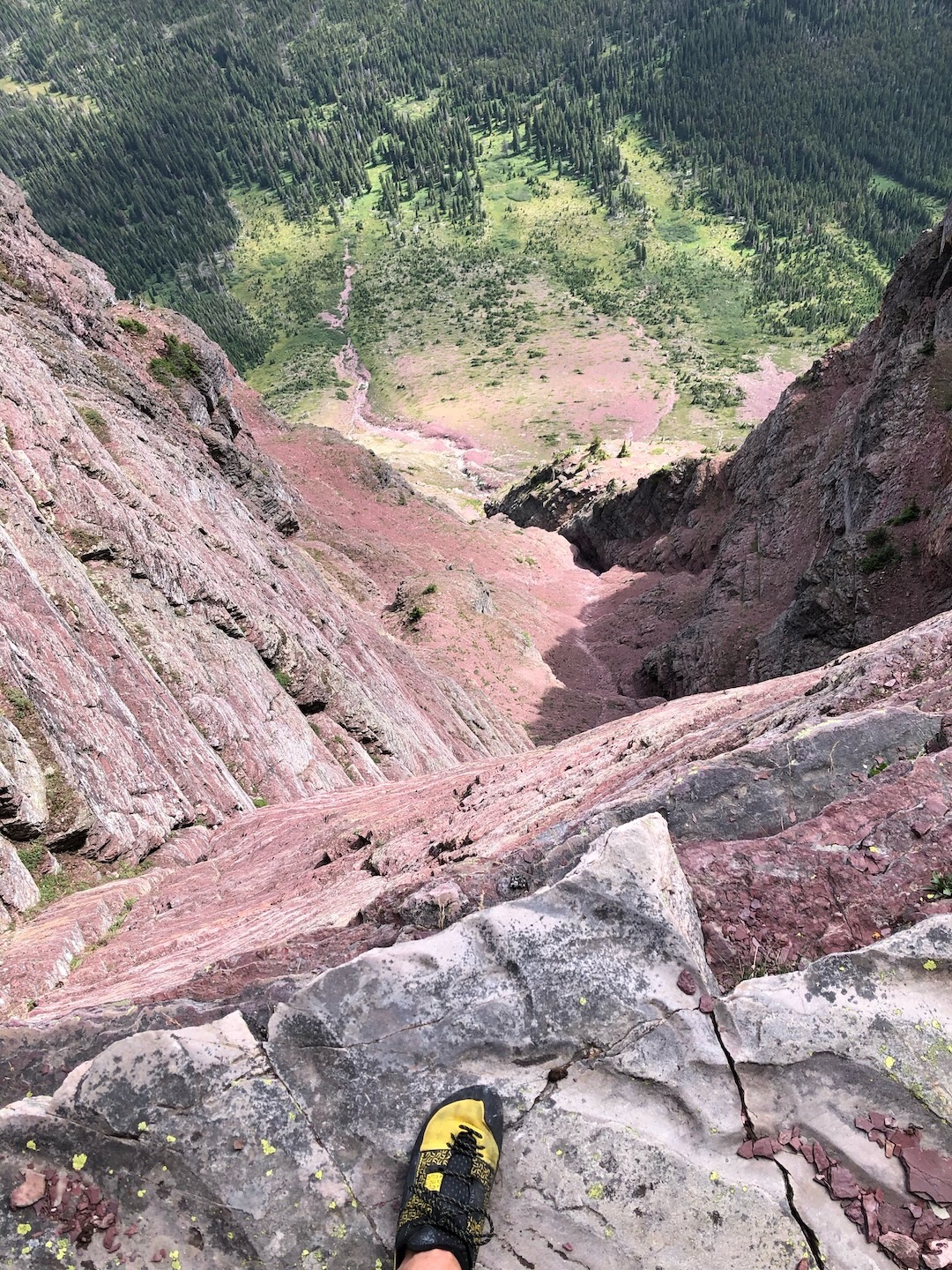 Looking down at the fourth- and fifth-class terrain leading to the headwall of solid red rock on the east face (1,800’, IV 5.9) of Sinopah Mountain. 