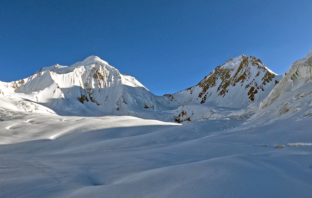 The north cwm of the Sim Gang Glacier with Peak 6,433m on the left and Virjerab Sar (6,616m GPS) at right, seen from the south. The two are separated by Virjerab Pass (ca 6,000m). The 2024 first ascent of Virjerab Sar reached the top from the opposite side. 
