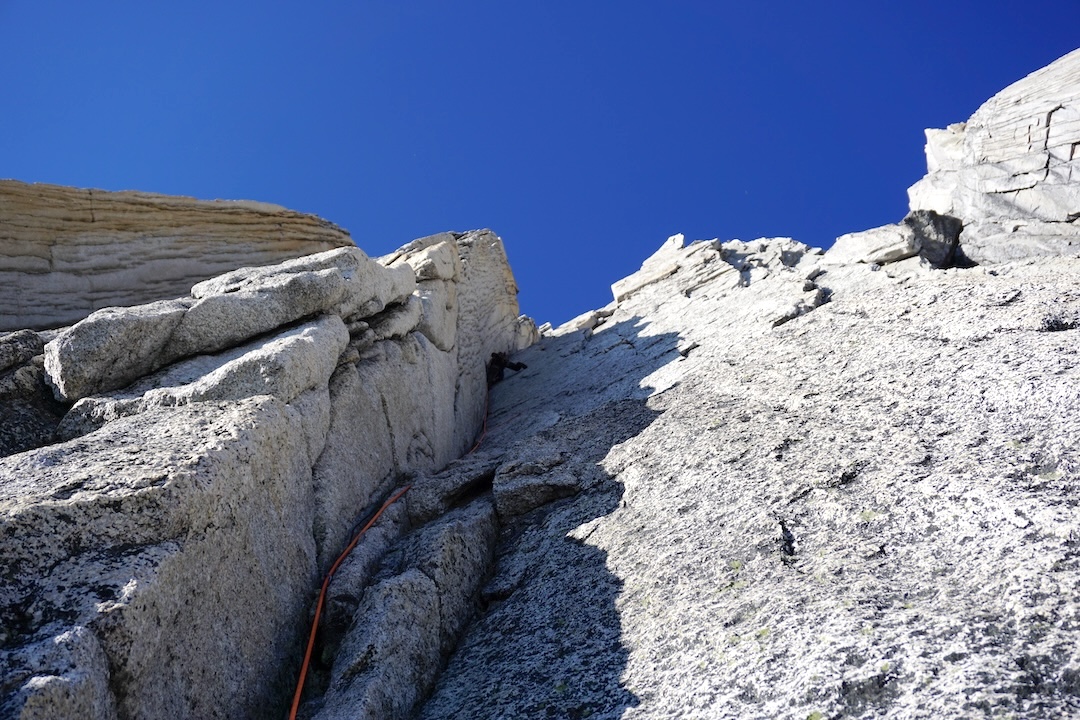 Ryan LaRocque on the second to last dihedral pitch of Rat Race (800m, 5.11+ A1) on the west face of North Howser Tower. 