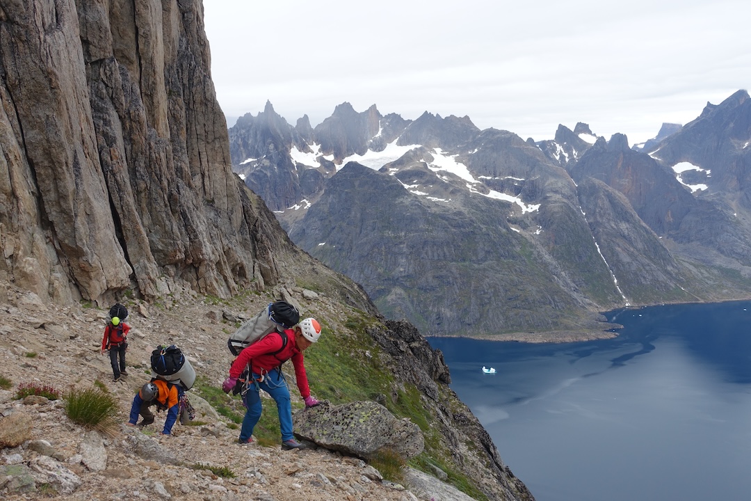 Traversing the midway ledge on Maujit Qaqarssuasia under heavy loads. Base camp was across the fjord by the cove in back right.