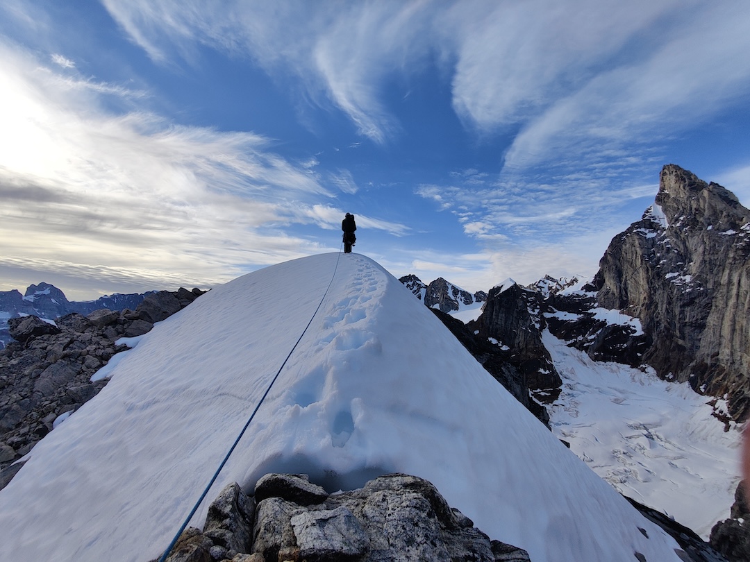 Daniele Bonzi on the snowy ridge of Molar Spire during the second day of the Trident VI Orobica (1,000m of climbing, V+) traverse, Fox Jaw Cirque, Schweizerland, East Greenland. 