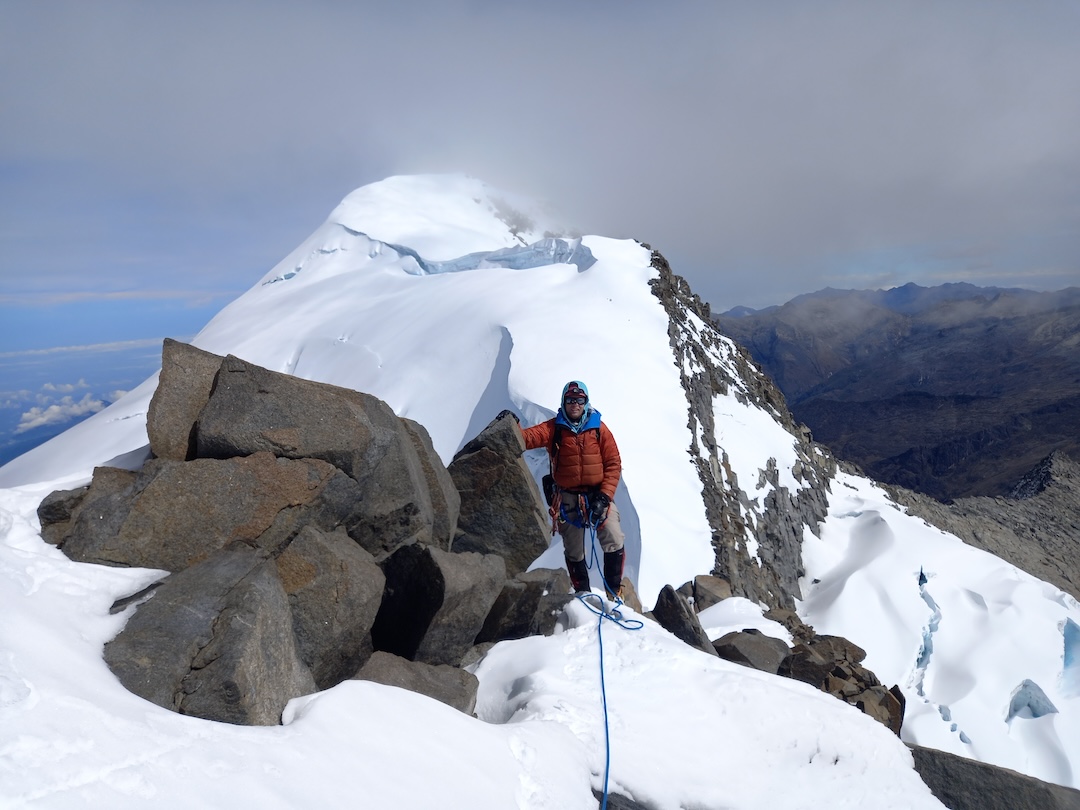 Eric Gilbertson on the east ridge of Pico Simón Bolívar above the upper rock step. Pico Cristóbal Colón in the background. 
