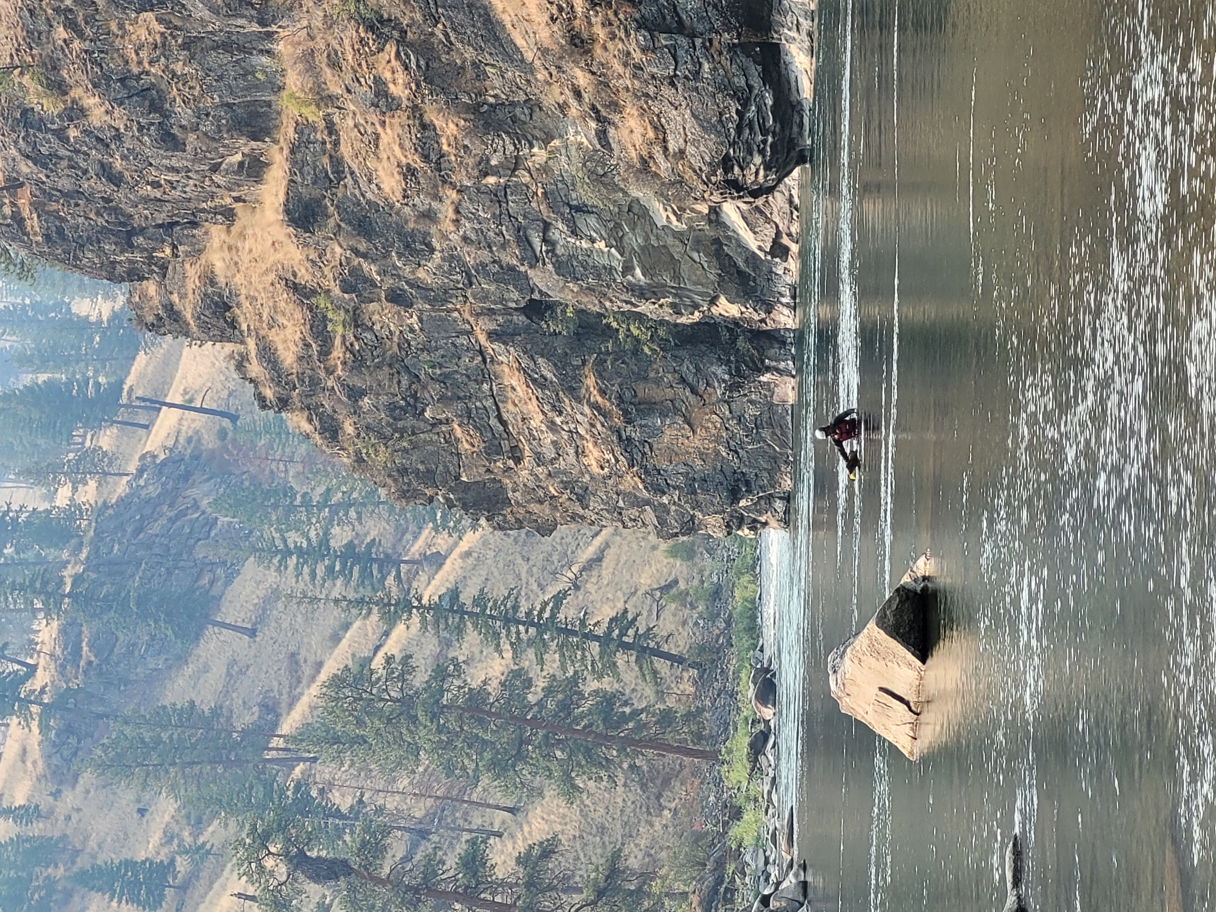 Ky Hart walks his backpack downstream in a shallow spot of the river, en route to the first ascent of the Redside Wall. 