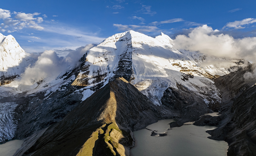 Chomolhari III (6,706m) in the center of the picture, with the north spur facing the camera. To the right is the pointed icy summit of Chomolhari II, with Chomolhari in cloud to the right again. On the left of the image is part of Jitchu Drake. 