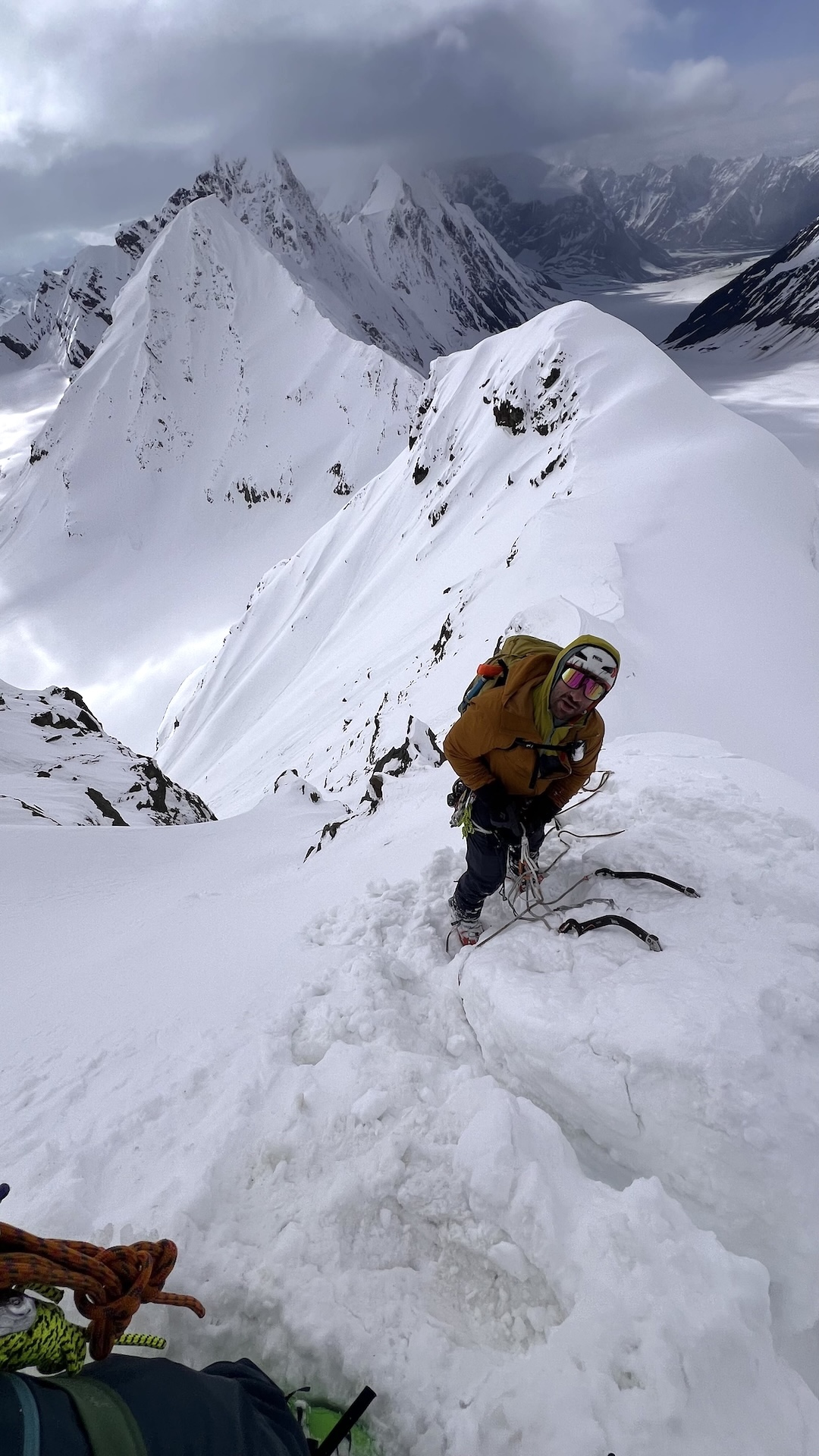 Eli Sturm rapping off a bollard after bailing on Point 8,350’. The east face of Mt. Hess is in the distance in the clouds.
