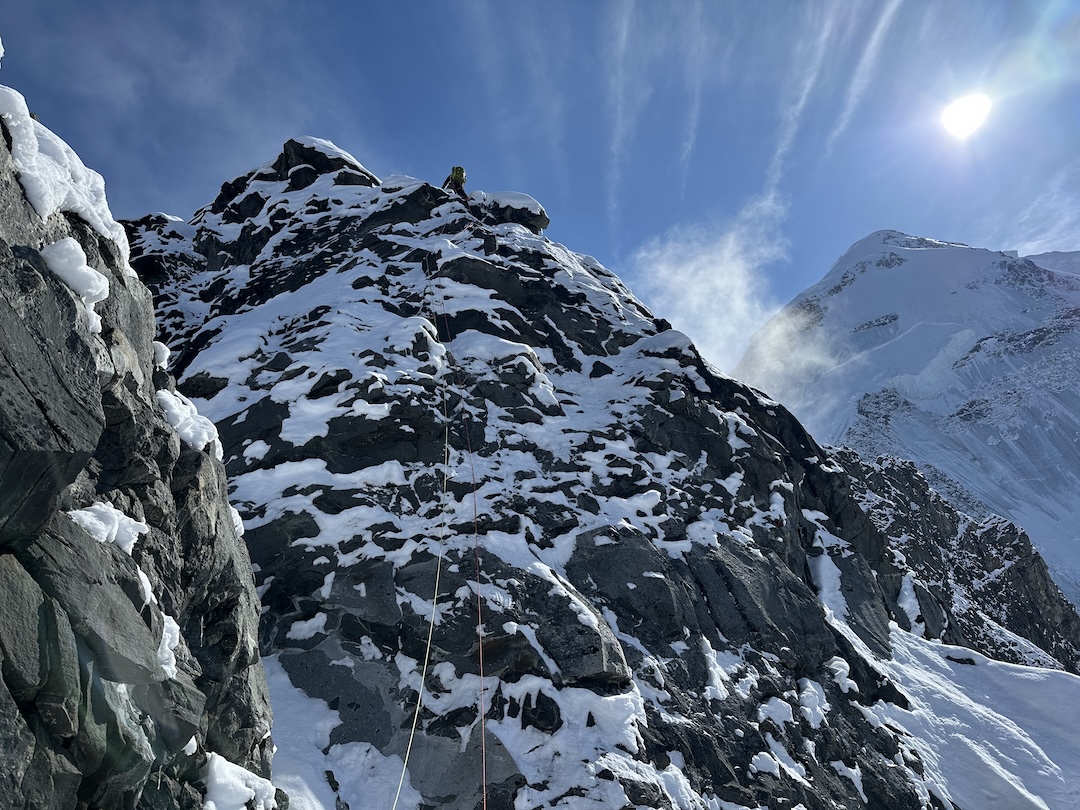 Cody Winckler climbing toward the top of the second major tower along the crux section of the Enthalpy Ridge, with the summit of Mt. Moffit visible in the right background. 