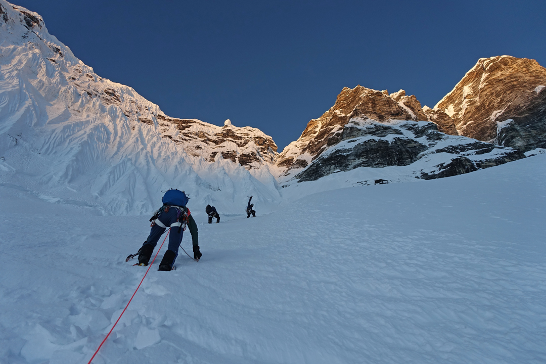 Partway up the east face of Kimshung, a little after dawn on October 20, 2025. The route climbed the ice and mixed couloir directly above to gain the south-southeast ridge. 