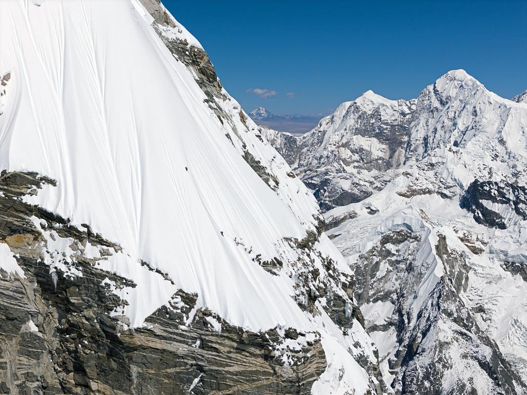 The climbers, with François Cazzanelli in the lead, starting up the steep sugary snow that forms the south-southeast ridge of Kimshung. In the background is Peak 6,837m (left, in Tibet) and Langtang Ri (7,205m). The distant peak across the Tibetan Plateau is Tsangla Ri (6,495m). 