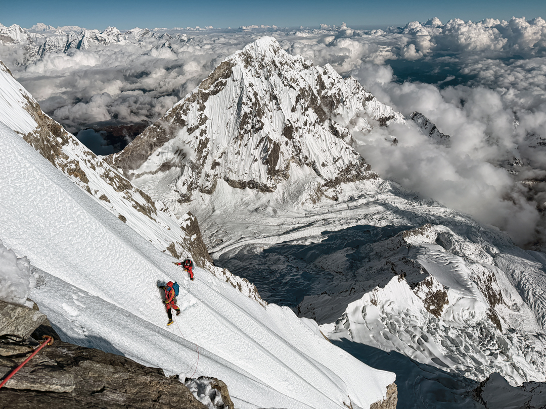 Adam Bielecki and Felix Berg negotiate a choppy sea of unconsolidated snow on the southeast face of Numbur. Behind, the west face of Karyolung (6,530m) rises above the upper Dudh Kund Glacier. 