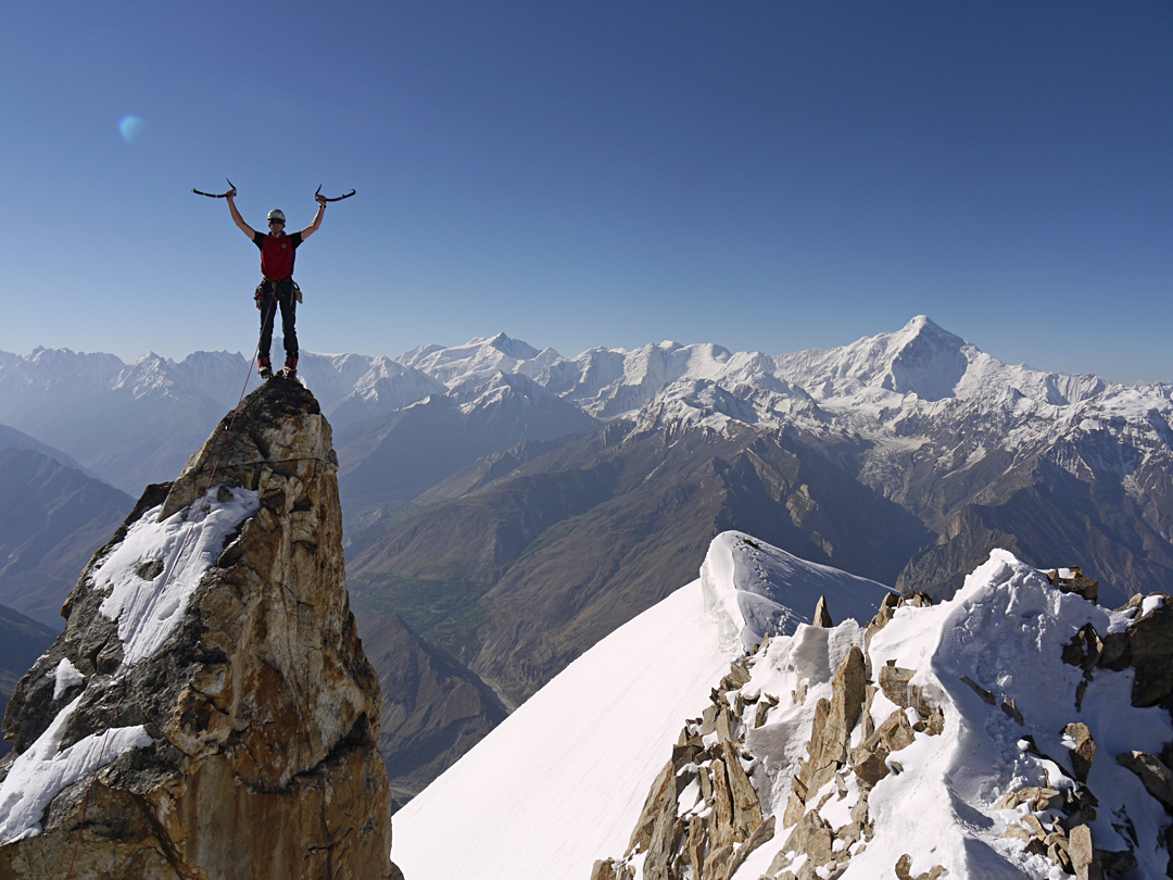 The view to the south over a small rock spire seen from the snowy summit of Sorry Peak (5,725m). Behind, the high summit on the left is Malubiting (7,453m), while that on the right is Diran (7,285m), with the north ridge facing the camera. Between the two lie the Miar/Phuparash Group (6,824m). 