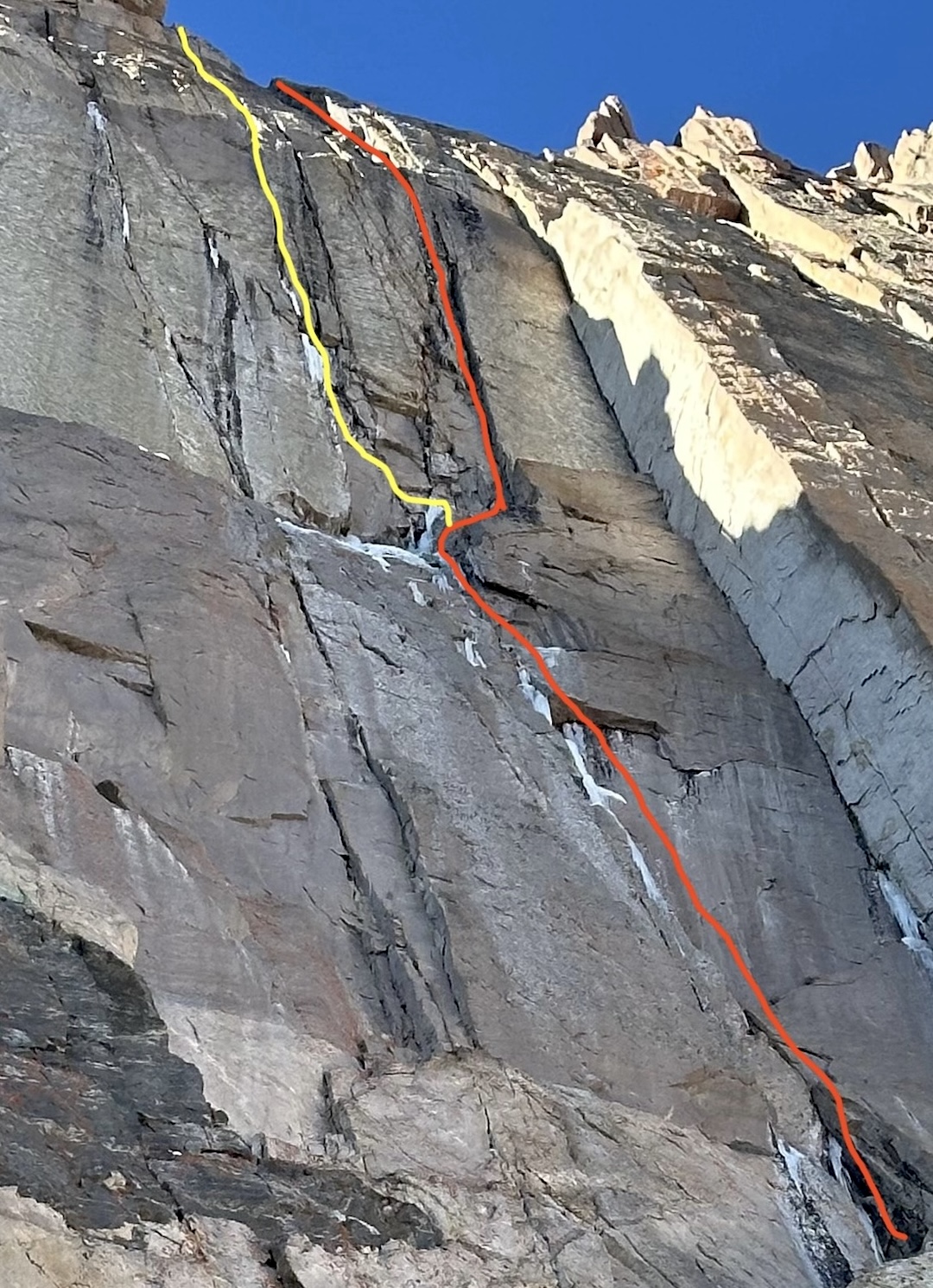 The upper northeast face of Longs Peak, showing (yellow line) Baknnator Indirect (WI5 M8) and (red line) Wobbly Baknn Strips (WI5 M7+). 