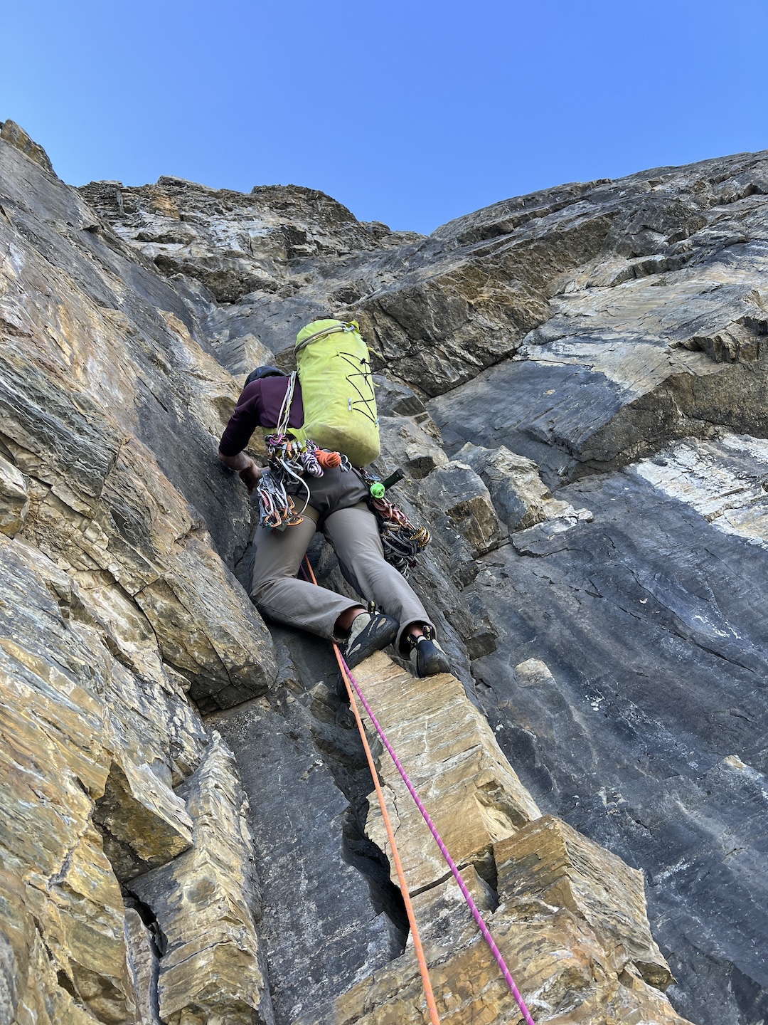 Greg Barrett standing atop loose blocks with unclimbed roofs looming overhead on the east face of Mt. Chephren. 