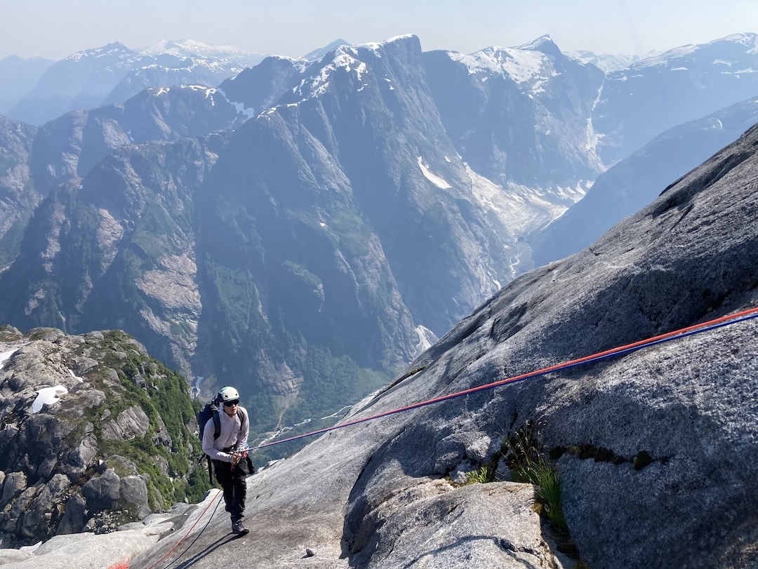 Savian Czerny rappelling back down to the bivy with the upper reaches of Middle Earth in the background. 