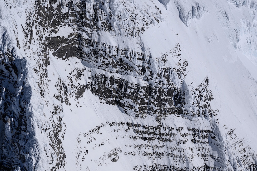High on Robson’s south face during the successful ski descent. One skier can be seen near the top, while another waits to traverse onto the rocky face and rappel to skiable terrain in The Great Couloir.