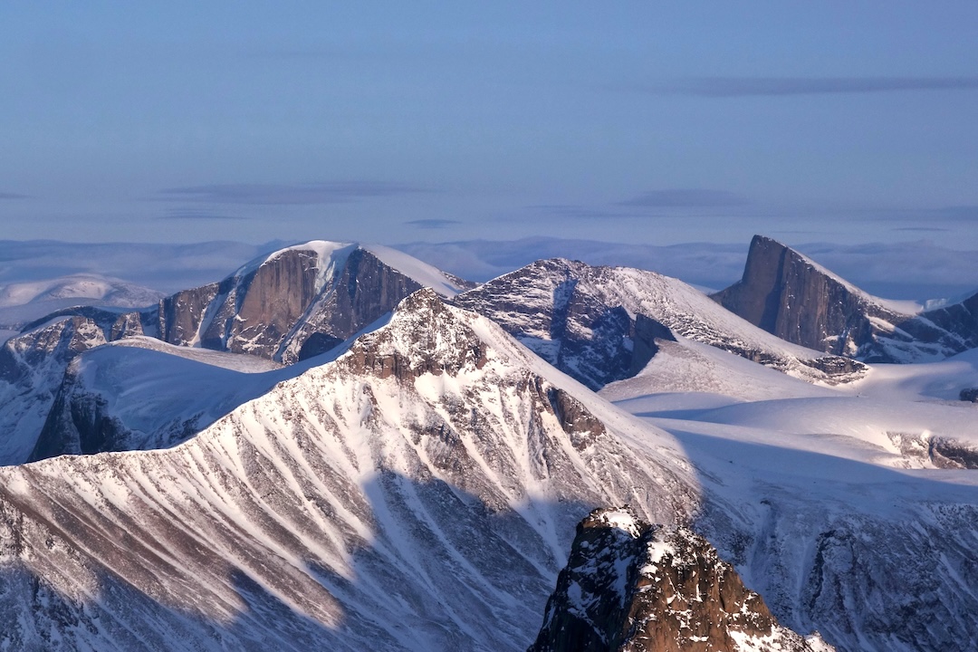 Walls northwest of Kingnait Fjord, at around 66.411926, -64.823659. The photo is taken from the summit of Minas Tirith, looking southeast over the area near the terminus of the Nerutusoq Glacier. The main peaks were climbed in 1977, but the walls are likely unclimbed. 