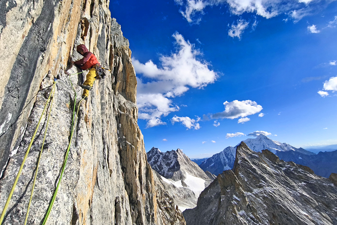 Luka Lindič on the rightward traverse of the headwall on Grad Kristalov, Peak 5,600m. The snow pyramid in the distance is Genyen (6,204m), the highest summit in the range.  