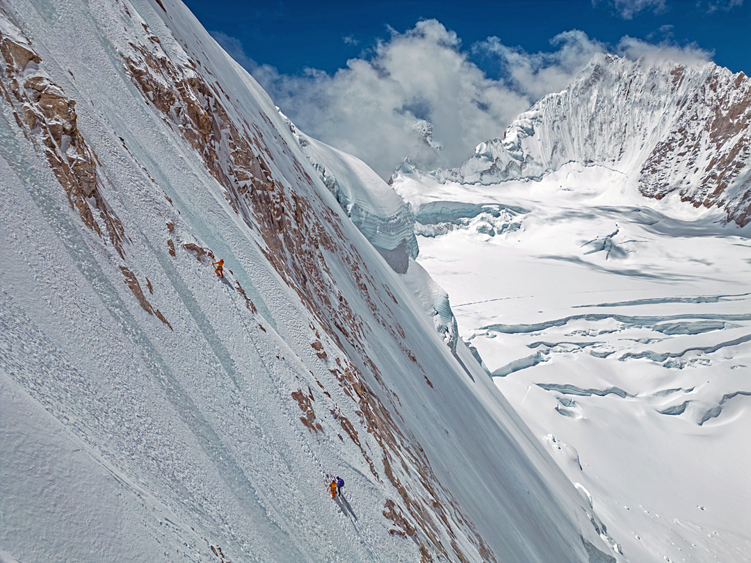 Drone photo of the three climbers on the northwest face of Kangmi Kangri in May 2024. Behind is the fluted, unclimbed northeast face of Karjiang (7,221m).