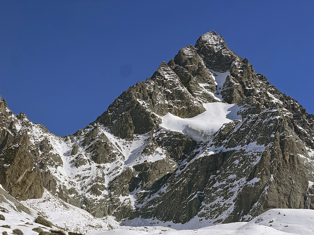 Lotus Flower Mountain seen from the west. The new route Safe Return Home climbs to the obvious col on the left, then traverses across to the (hidden) north face. From the summit, the two climbers descended the left skyline ridge to the first couloir that slants down right. They used this to reach the large hanging glacier in the middle of the face, from where they descended to the bottom of the wall not far from their starting point. The first ascent of the peak in 1998 was on the south side, beyond the right skyline. 