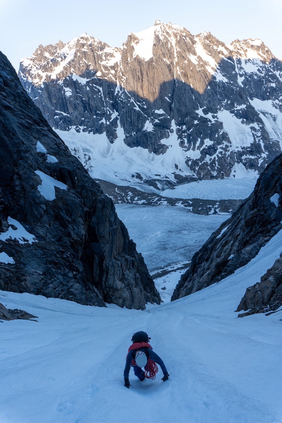 Robbie Milne in the approach couloir on Optimisme (930m, 11 pitches, TD+ 6b M5), with the frozen Lake Taserssuaqb below and the Three Castles in back. 