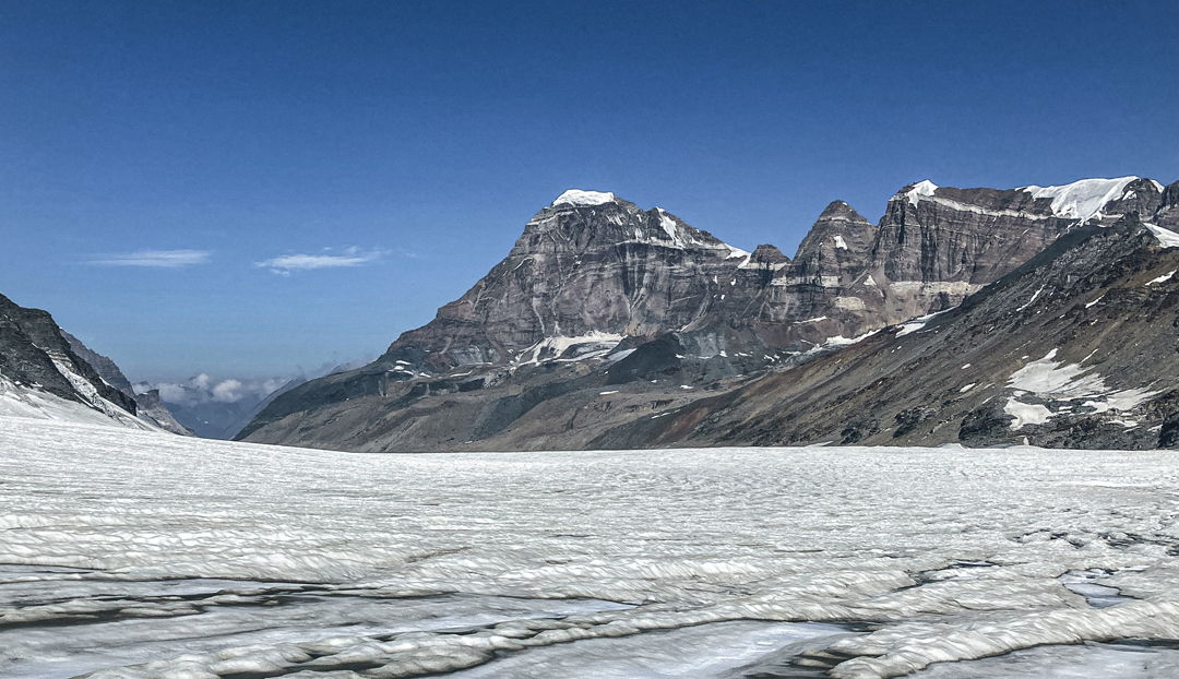 On the Barmal Glacier looking west. The large peak in the center is Snowy Peak 10, while the broad, horizontal-topped peak on the right is D 42 (highest point at left end). Both appear to have no documented ascent.  