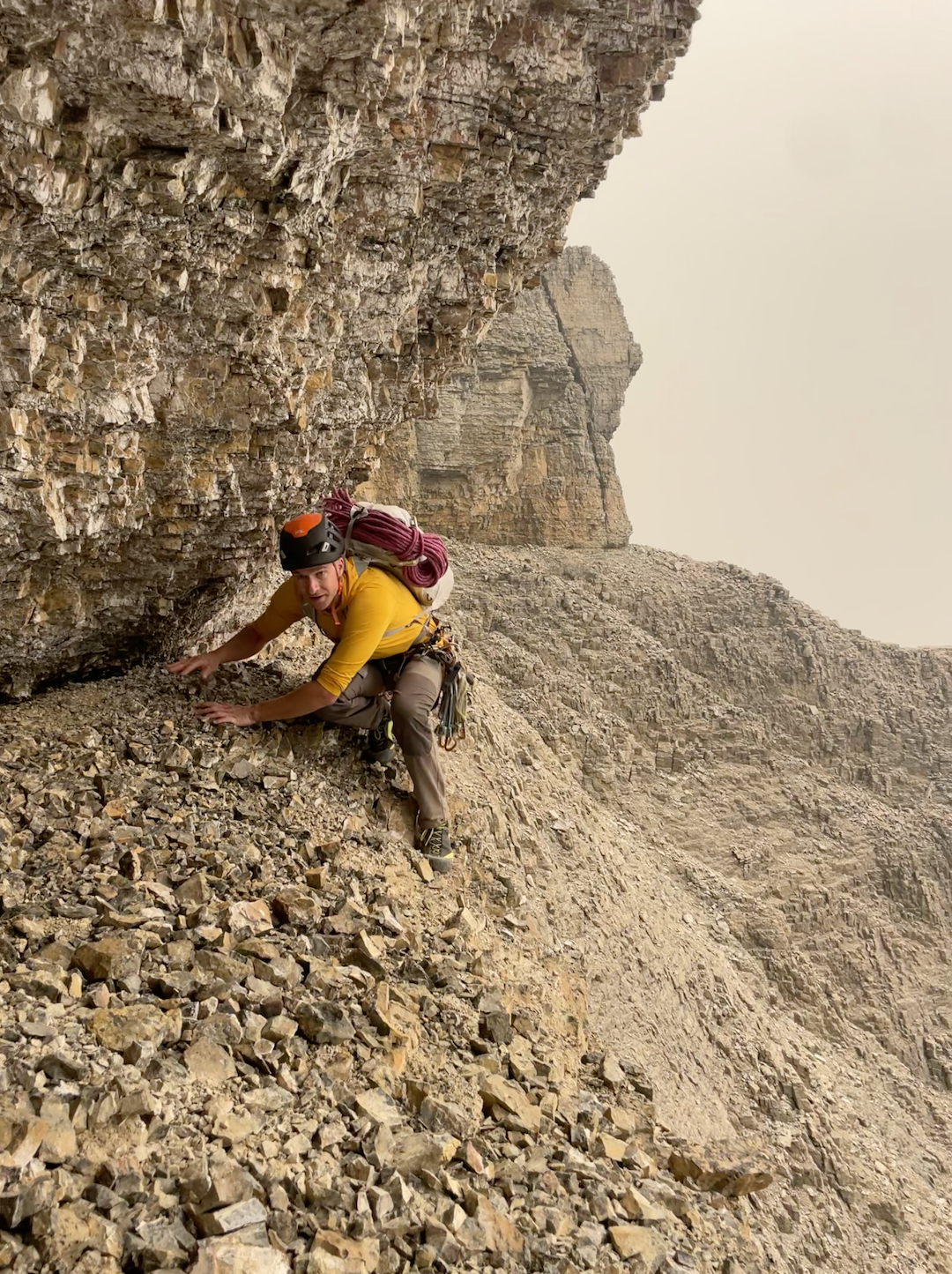 Greg Barrett crawling along a ledge to reach the final tower before the summit of Stutfield Peak East. 
