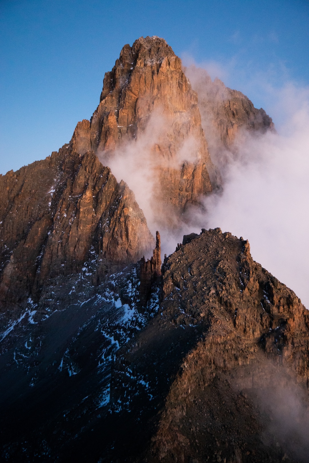 Nelion at sunrise, seen from Point Lenana to the east. The Normal Route up Nelion, the southeast face and ridge, angles up from the left to the summit. The classic East Face route is lit up by the sun. Batian, the mountain’s highest point, is hidden in back.