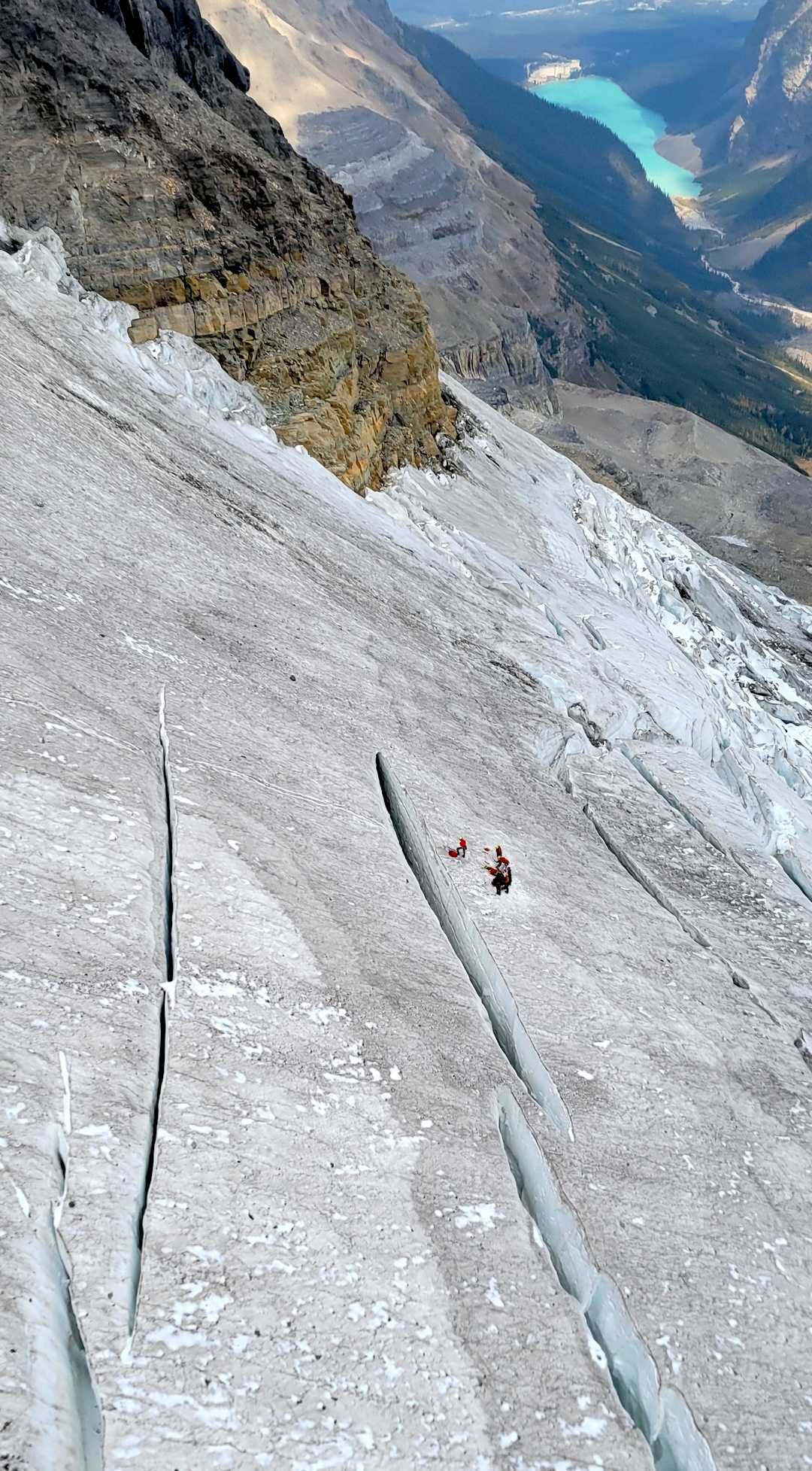 
The tracks left by a sliding climber before they plunged into a crevasse are visible above the rescue party. Parks Canada