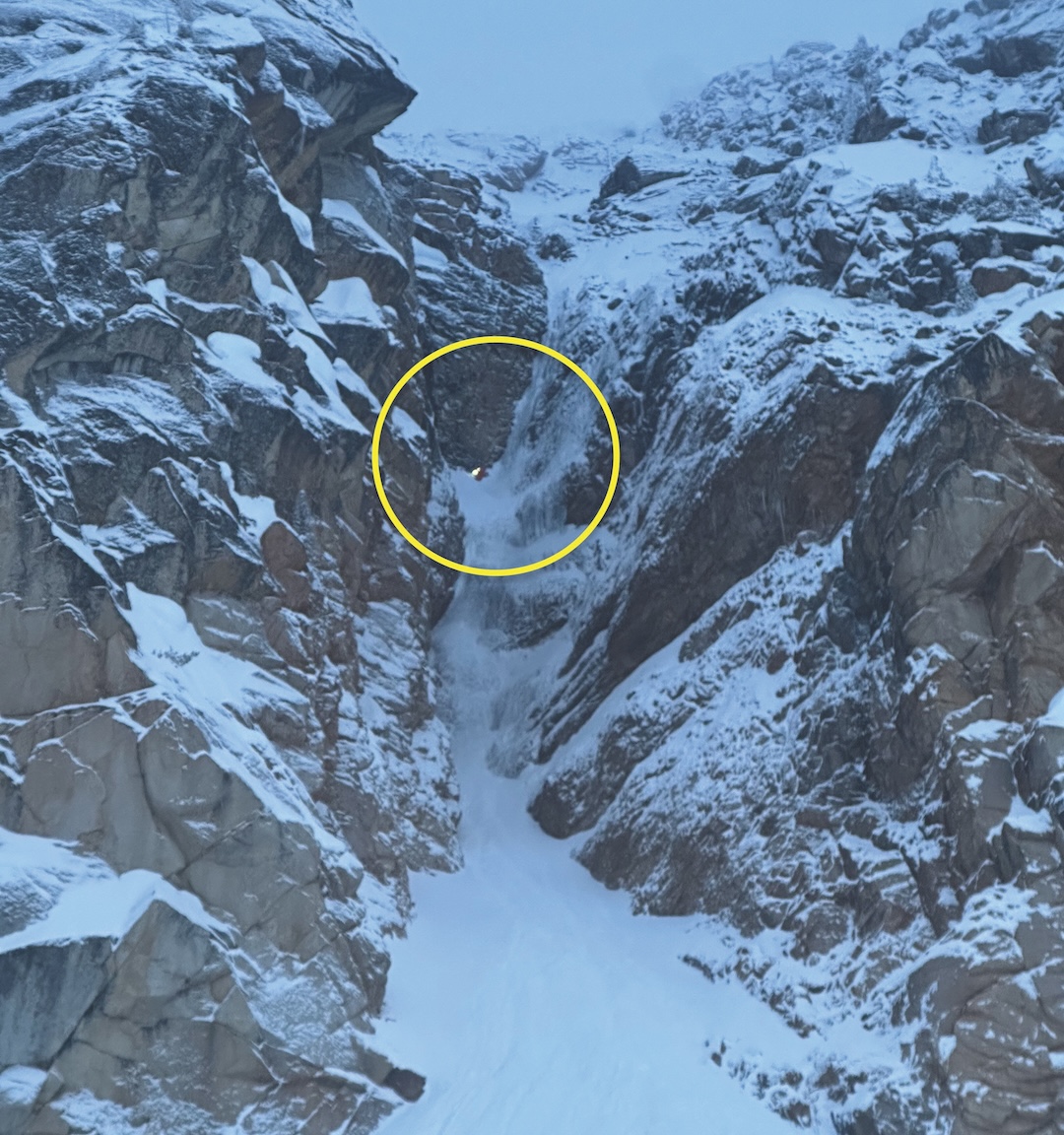Thomas Gilbert (yellow circle) is showered by spindrift at the belay/rappel station on the Cauthorn-Wilson Route on Cutthroat Peak. He was stranded overnight one pitch above the ground after his partner fell while rappelling, taking the ropes with him.